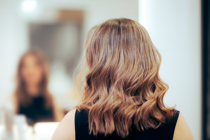 Rückansicht einer Person mit kinnlangen, leicht gewellten Haaren im Friseursalon.