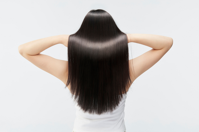 Langes glattes dunkles Haar, rueckenansicht mit Haenden im Nacken
