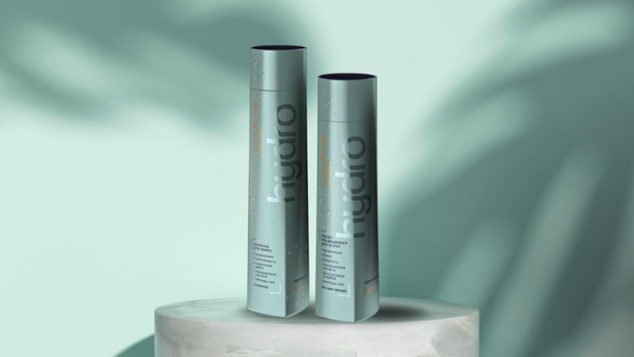 Zwei helltürkise Flaschen ESTEL Haute Couture HydroBalance Shampoo und Balsam-Maske stehen auf einem Podest vor grünem Hintergrund mit Schatten.