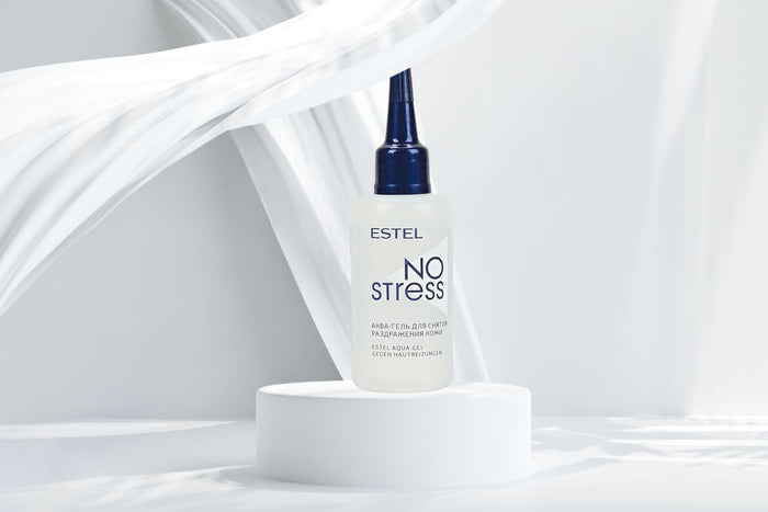Flasche Estel NO STRESS Aqua-Gel gegen Hautreizungen auf weißem Podest mit transparentem Stoff im Hintergrund.
