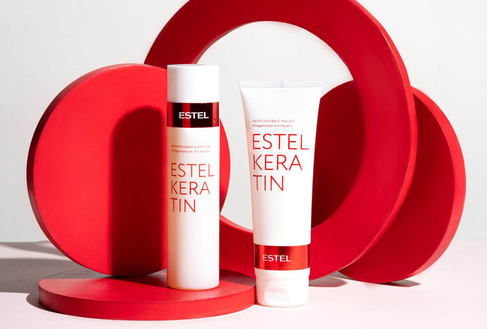 Zwei ESTEL KERATIN Produkte vor roten Deko-Elementen, Shampoo und Maske in weißen Tuben mit rotem Akzent.