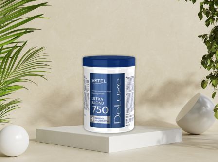 Dose Estel DeLuxe Ultra Blond 750 g Blondierpulver mit blauem Deckel, platziert auf Podest zwischen dekorativen Pflanzen.