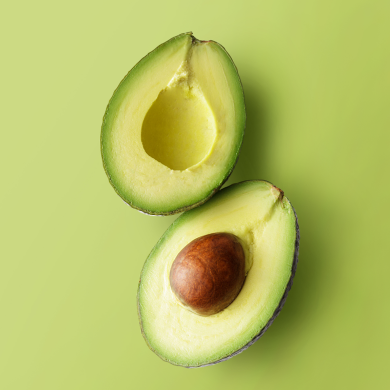 Zwei Hälften einer Avocado vor hellgrünem Hintergrund, eine Hälfte mit braunem Kern, die andere ohne.