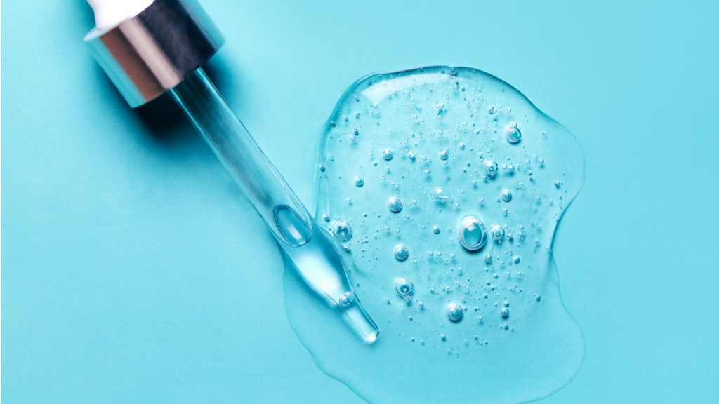 Dekorative Darstellung von Milchsäure: Pipette mit durchsichtigem Gel und Luftblasen, auf türkisfarbenem Hintergrund.