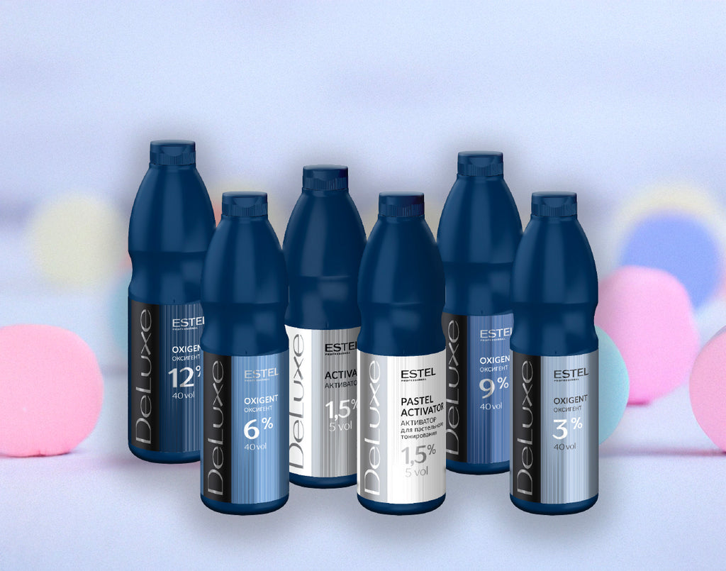 ESTEL DeLuxe Set: Sechs dunkelblaue Flaschen Oxigent und Activator in verschiedenen Konzentrationen von 1,5 % bis 12 %, vor hellem Hintergrund mit farbigen Lichteffekten.