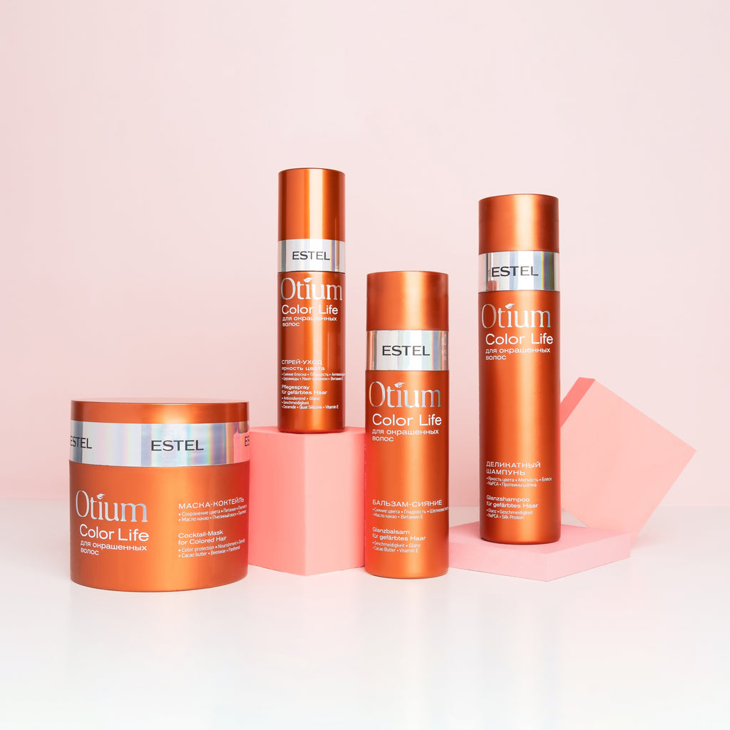 ESTEL Otium Color Life Pflegeset für coloriertes Haar: Kupferfarbene Dose Maske, zwei Flaschen Shampoo und Balsam sowie Sprayflasche, vor rosa Hintergrund arrangiert.