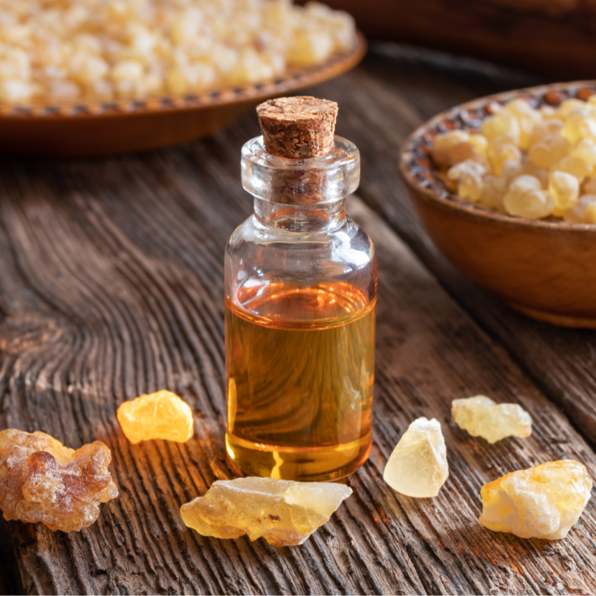 Kleines Glasfläschchen mit bernsteinfarbenem Harzöl, umgeben von hellen und dunklen Harzstücken auf einem rustikalen Holztisch – dekorative Darstellung von Festigungsharzen.