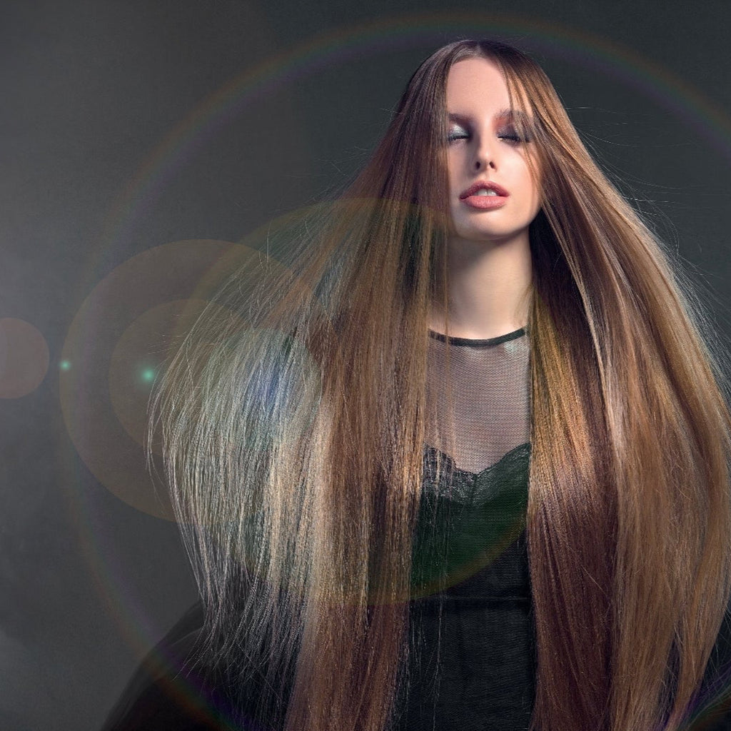 Frau mit langem, glattem, glänzendem Haar vor dunklem Hintergrund mit Lichtreflexen