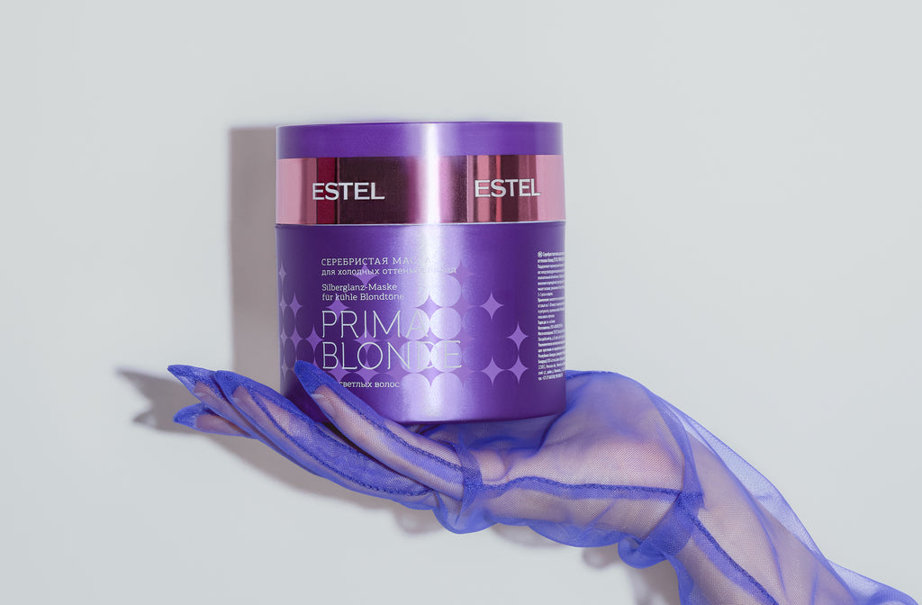 Lila Dose Estel Prima Blonde Silberglanz-Maske wird von einer Hand in transparentem violetten Handschuh gehalten